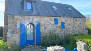 A stone house with a gabled roof, a chimney, and a small skylight.
