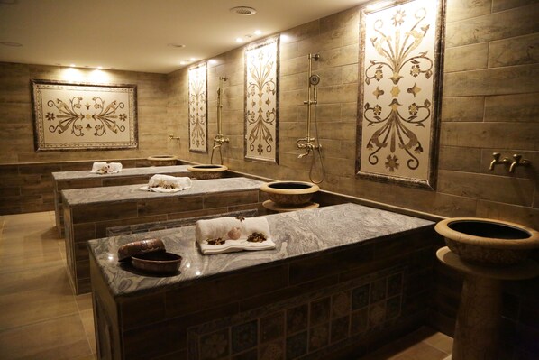 A spa area with multiple massage tables, a large decorative mirror, and a stone basin. - Opal Hotel Amman (Amman)