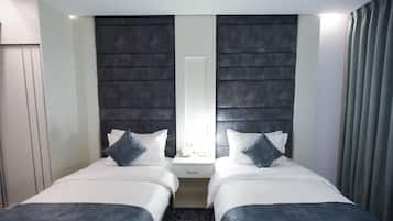 A hotel room with two beds, a nightstand, a mirror, and a window with curtains.