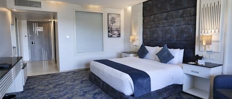 A modern hotel room with a large bed, bedside tables, a desk, and a chair.