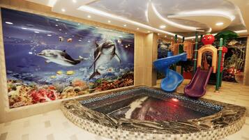 Kids can play and explore in this vibrant play area featuring a large underwater mural and a fun slide.