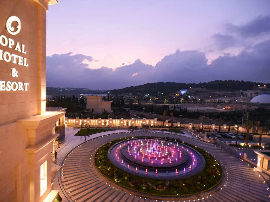 Exterior del Hotel & Resort Opal con una fuente circular y jardines ajardinados.