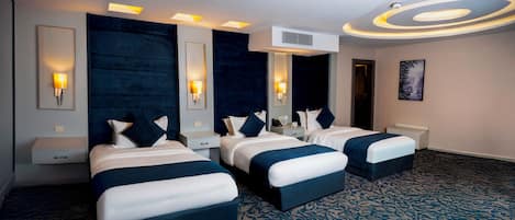 Habitación de hotel con tres camas, una pared de acento oscura y llamativa, e iluminación moderna.