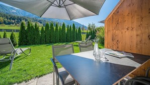 Een terras met een tafel, stoelen en een grote parasol.