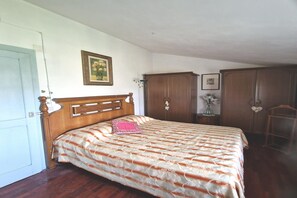 Une chambre à coucher avec un lit en bois, une armoire, une table de chevet et un tableau encadré au mur.
