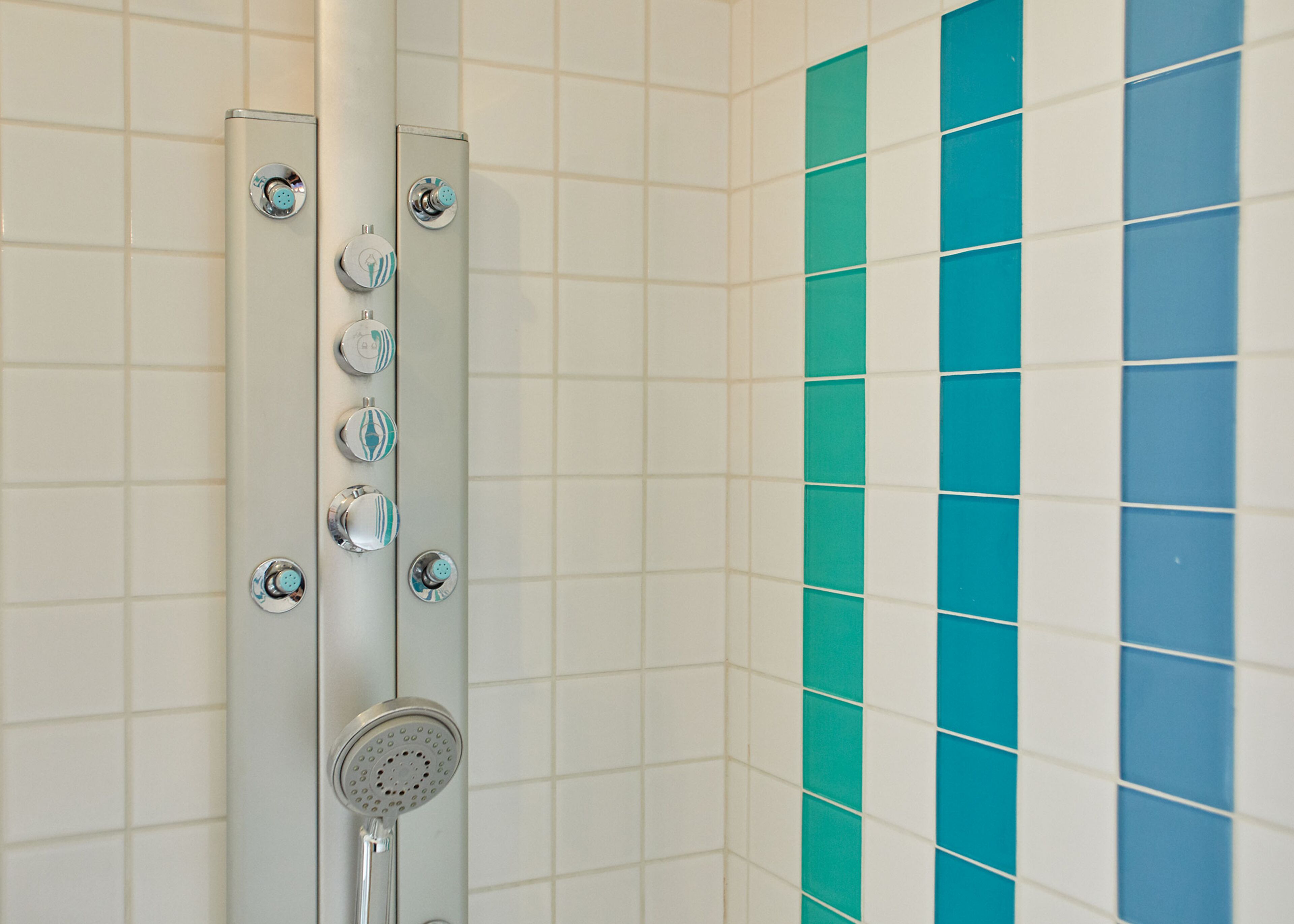 A shower with multiple control knobs and a handheld showerhead.