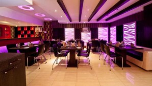 Um restaurante moderno com diversas áreas de refeição, incluindo um bar e uma seção para eventos privados.