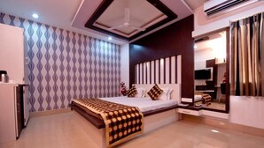 Quarto moderno com cama grande, secretária embutida e televisão.
