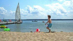 A sandy beach with a sailboat and a rowboat in the water.