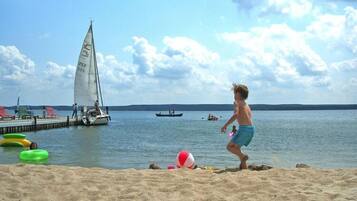 Una playa arenosa con un velero y un bote en el agua.
