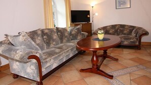 A living room with two sofas, a round wooden coffee table, a flat-screen TV, and a framed picture on the wall. - Ferienwohnanlage Gut Bundhorst, Stolpe (Stolpe)