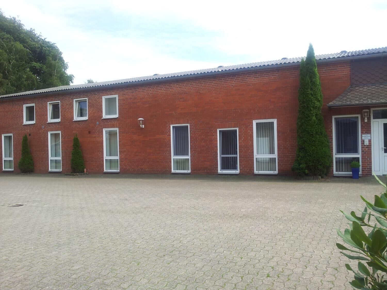Un edificio de ladrillo rojo con varias ventanas y un patio empedrado.