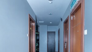 A hallway with carpeted floors, wooden doors, and a ceiling light. - Capital O 89538 Ocean Hotel (Labuan)