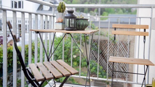 A balcony with a wooden table, two chairs, and potted plants. - l'En Vert (Bagnères-de-Bigorre)