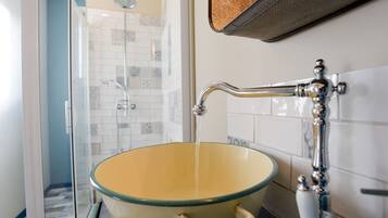 A bathroom with a glass-enclosed shower, a yellow basin, and a wall-mounted faucet.
