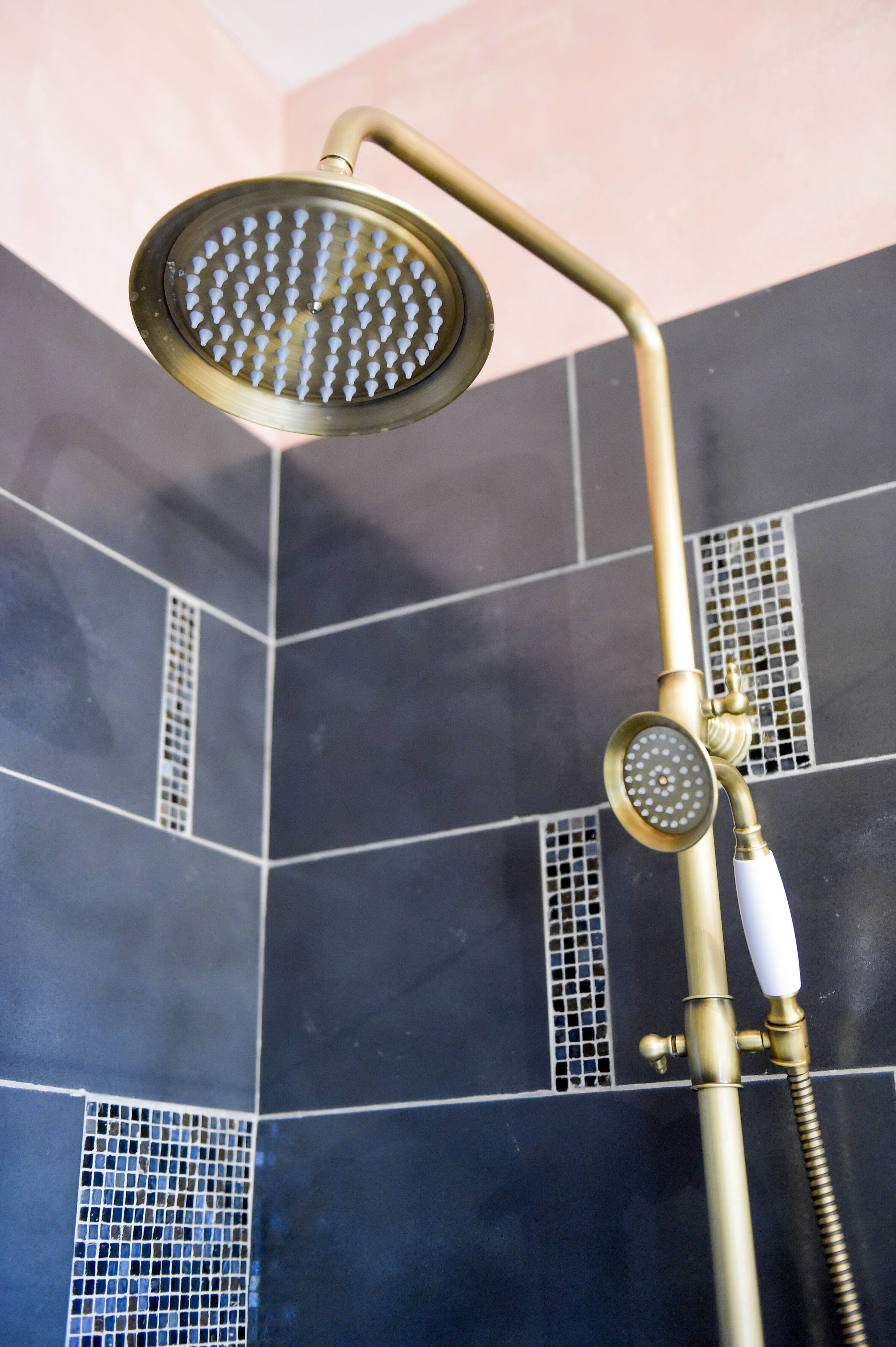 Une douche avec un pommeau de douche de couleur dorée et un tuyau blanc.