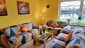 Ein Wohnzimmer mit einer Sofagarnitur, einem Glastisch und Seeblick durch ein Fenster.