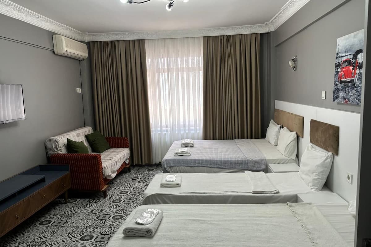 A hotel room with two beds, a sofa, a patterned floor, and a painting on the wall.