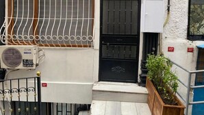 A residential building with a black gate, a white wall, and a small garden area. - Mara Suite Taxim (Istanbul)
