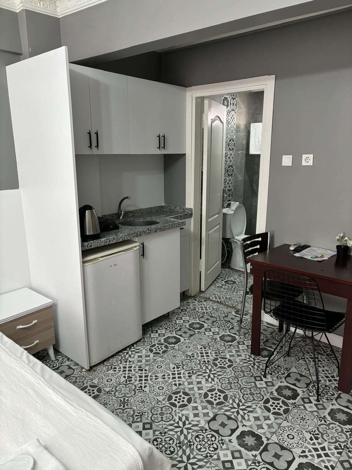 A compact kitchen with a refrigerator, sink, and a dining area with a table and chairs.