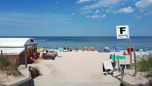 A beach with a sandy walkway, umbrellas, and a sign indicating a water sports area. - Holiday Home in Misdroy near Baltic Sea (Miedzyzdroje)