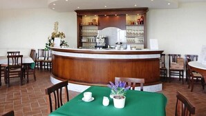 A reception area with a wooden counter, a coffee machine, and shelves with glassware and bottles. - Estate in Monte Serra with Pool & Olive Trees (Pisa)