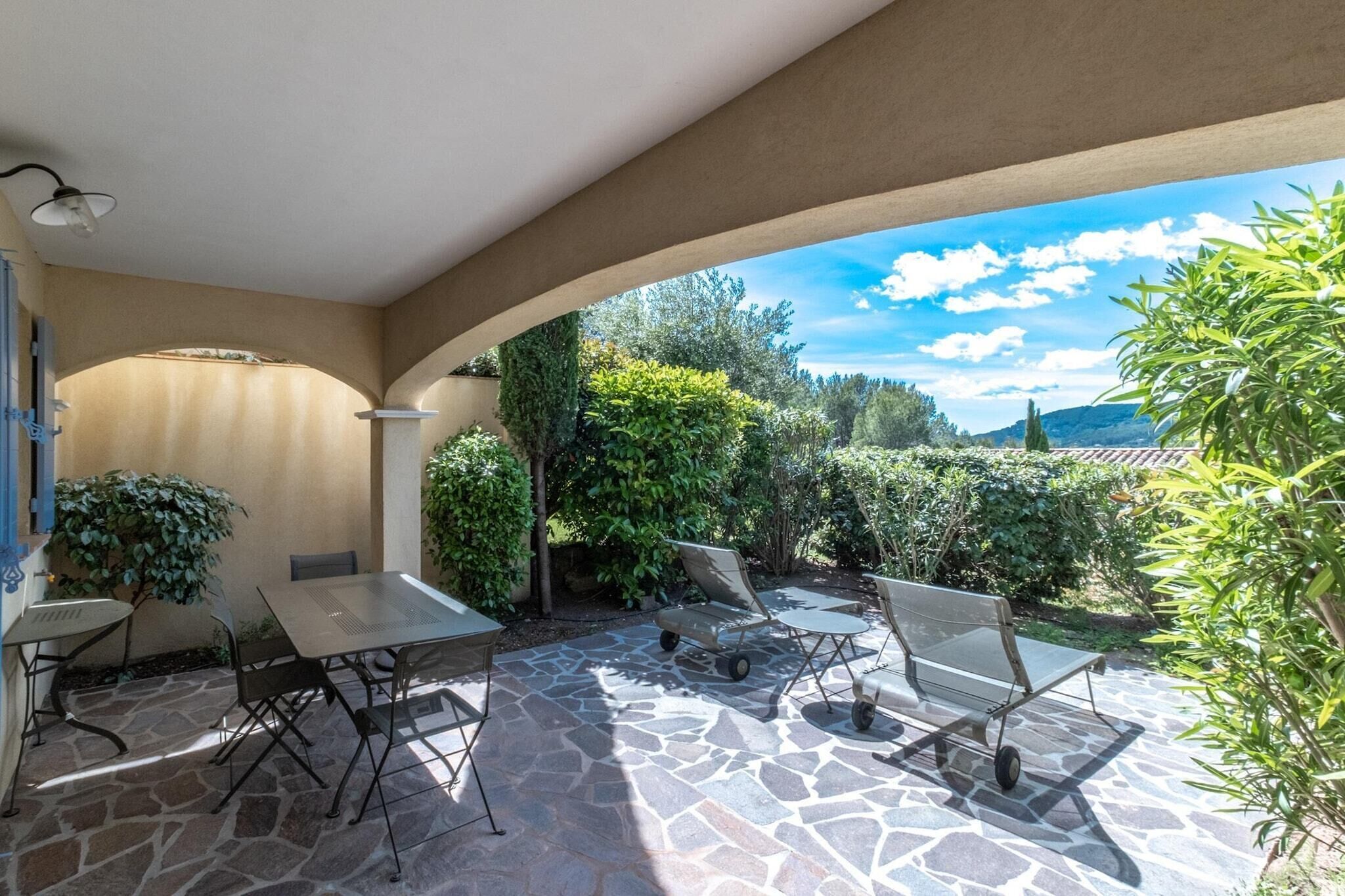 Une terrasse extérieure avec un sol en pierre, une table, des chaises et une pergola.