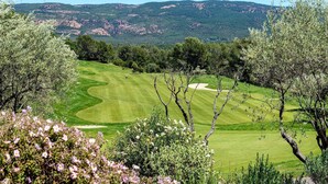 Un parcours de golf offrant une vue dégagée sur le paysage environnant, notamment sur les collines et les arbres.