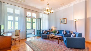 A living room with a blue sofa set, a wooden coffee table, and a patterned rug. - SEETELHOTEL Villa Waldesruh (Heringsdorf)
