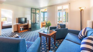 A living room with a sofa, a coffee table, a television, and a patterned carpet. - SEETELHOTEL Villa Waldesruh (Heringsdorf)