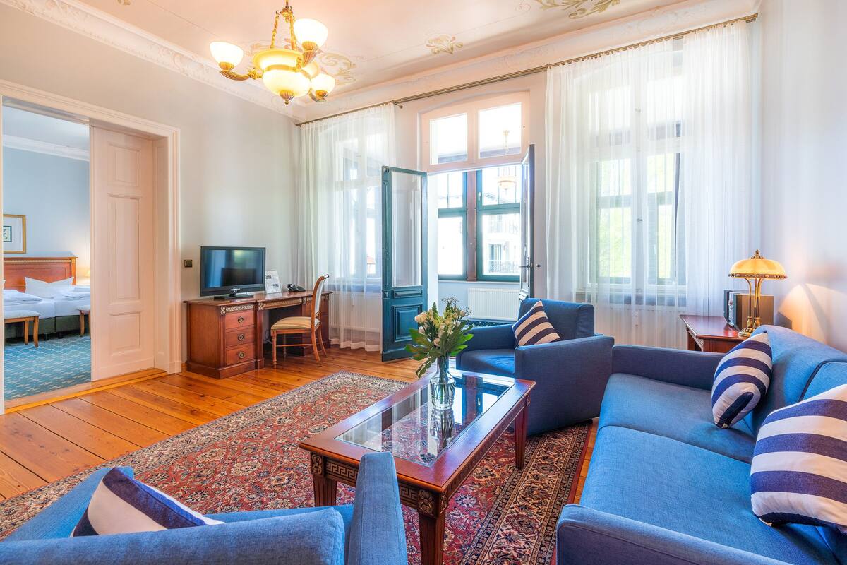 Una sala de estar con un sofá, sillones, una mesa de centro y un televisor.