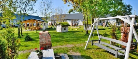 A residential area with a wooden deck, a swing set, and a brick structure.