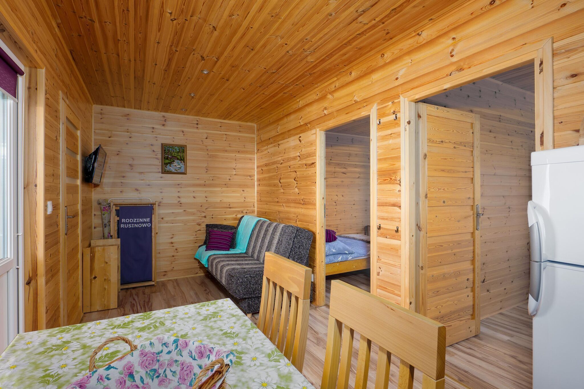 Eine Holzhütte mit einer Couch, einem kleinen Tisch und einem Kühlschrank.