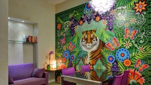 Un espace repas agrémenté d’une fresque murale colorée, d’un canapé violet et d’une table avec des chaises.