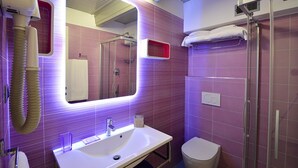 Une salle de bain moderne avec un grand miroir, un lavabo, des toilettes et une douche.
