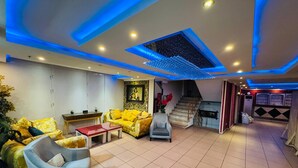 Una sala moderna con sofá, sillón y mesa de centro, una escalera que conduce a un nivel superior y una pared decorativa con un cuadro enmarcado.