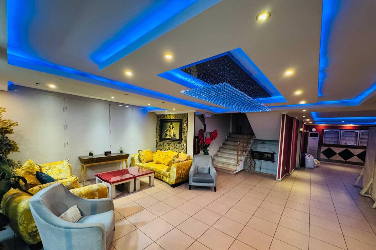 Un salon moderne comprenant un canapé, un fauteuil et une table basse, un escalier menant à un niveau supérieur et un mur décoratif orné d’un tableau encadré.