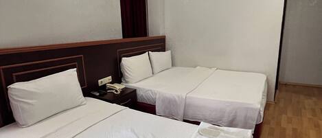 Habitación de hotel con dos camas, piso de madera, cortina roja e iluminación instalada en la pared.