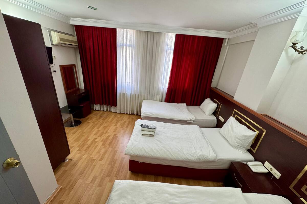 Une chambre d’hôtel avec deux lits, un bureau, une chaise et un miroir.