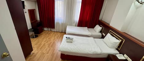 A hotel room with two beds, a desk, a chair, and a mirror.