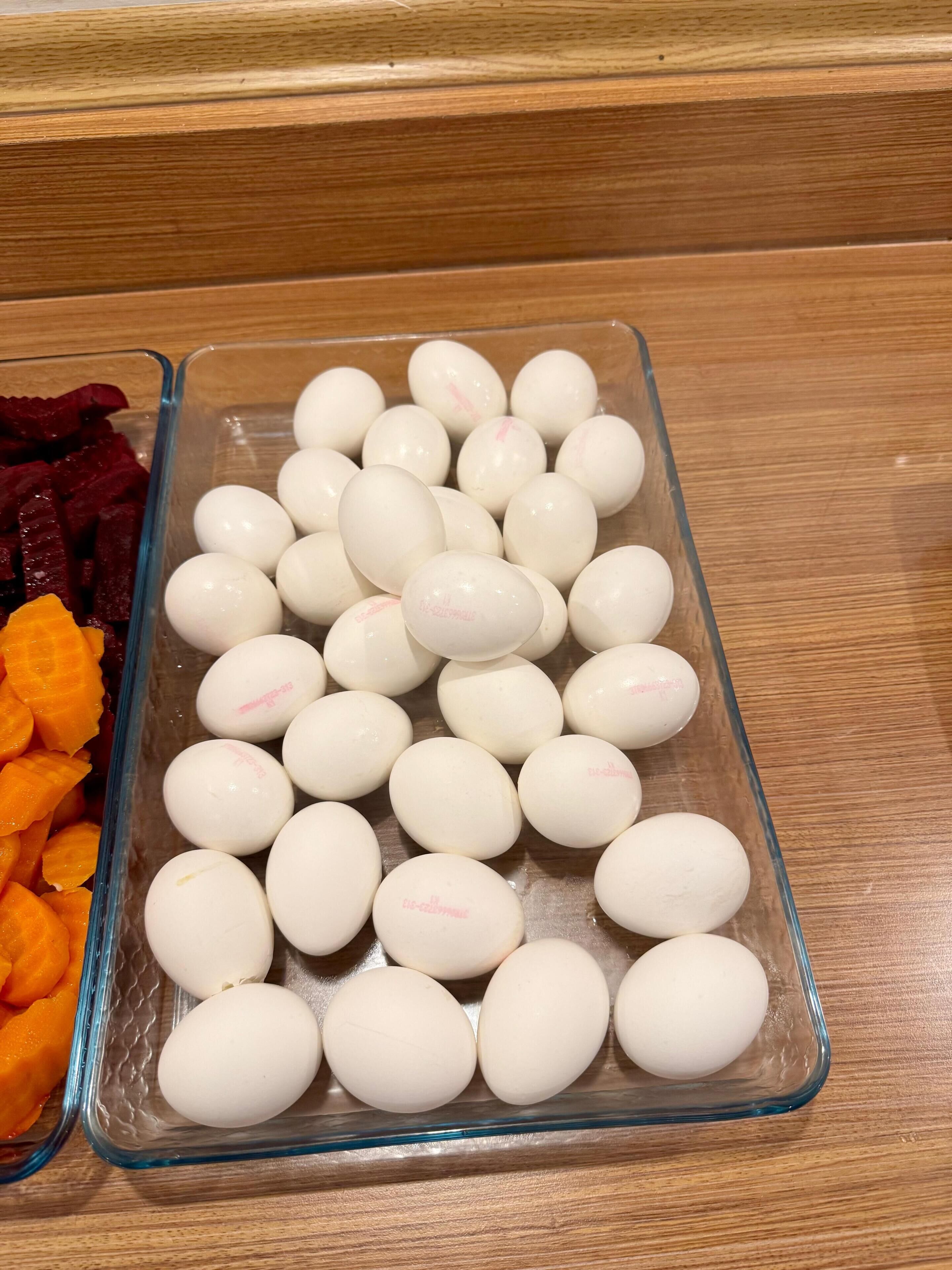 Un recipiente de vidrio con huevos blancos y remolachas deshidratadas sobre una superficie de madera.
