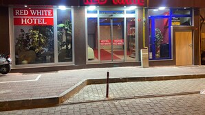 El exterior del Hotel Red White, con un llamativo letrero de neón, puertas de vidrio y una entrada visible.
