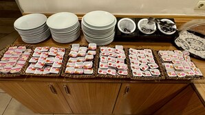 Montaje de bufé con varias pilas de platos, cuencos y cestas con alimentos envasados.