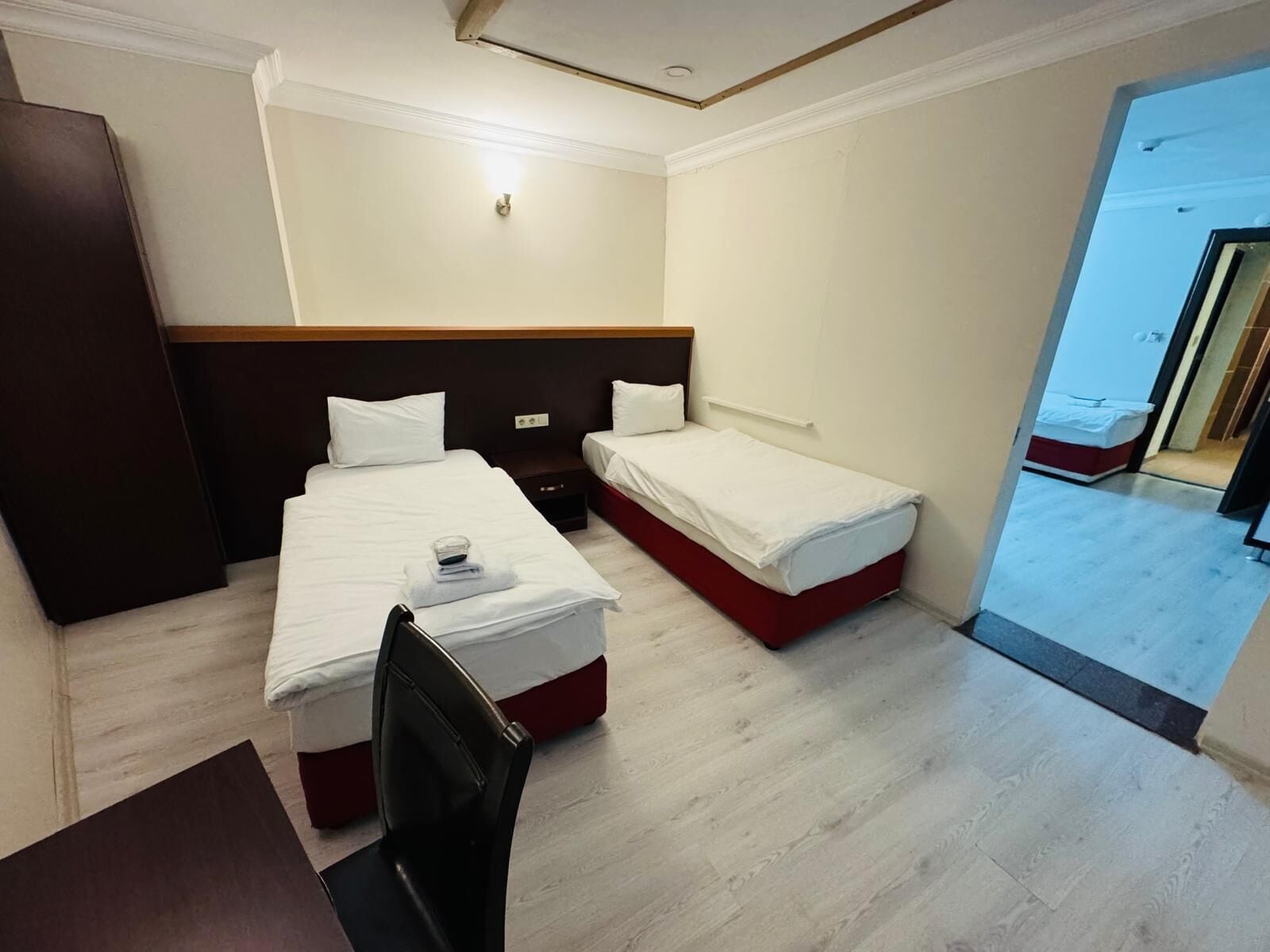 Een hotelkamer met twee bedden, een bureau, een stoel en een kledingkast.