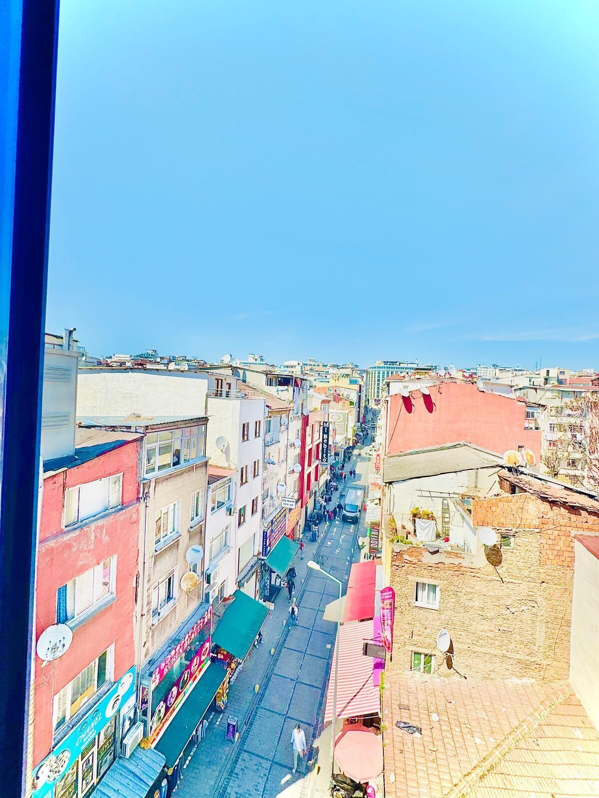 A street view with buildings, shops, and a clear sky.