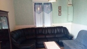 A living room with a black leather sofa, a wooden coffee table, and a grey armchair. - Serene holidays in Soulac sur Mer (Soulac-sur-Mer)