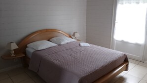 A neatly made bed with a wooden headboard, two bedside lamps, and a window with blinds. - Serene holidays in Soulac sur Mer (Soulac-sur-Mer)