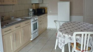 A compact kitchen with a stove, microwave, and sink. There is a dining table with chairs and a refrigerator in the background. - Serene holidays in Soulac sur Mer (Soulac-sur-Mer)