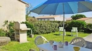 A patio with a table, chairs, and a blue umbrella. - Serene holidays in Soulac sur Mer (Soulac-sur-Mer)
