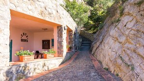 Un étroit sentier de pierre mène à un bâtiment à la façade en pierre, sur lequel on peut lire l’inscription « LOFT QUINTA ».